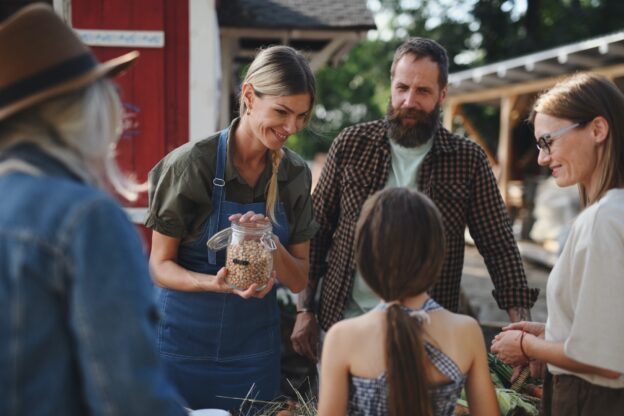 Little girl with her mother buying organic vegetables outdoors at community farmers market