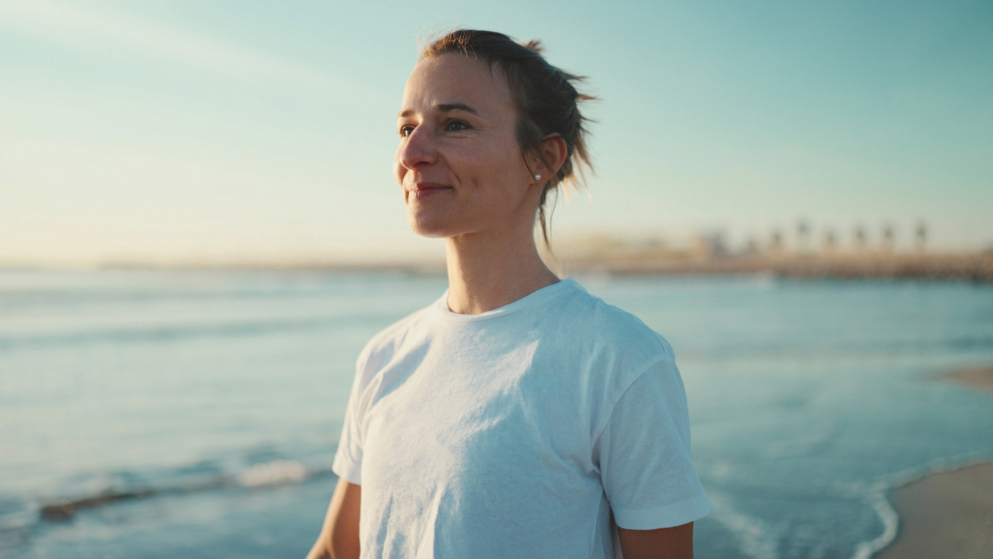 attractive blond woman looking happy walking along the sea after yoga practice