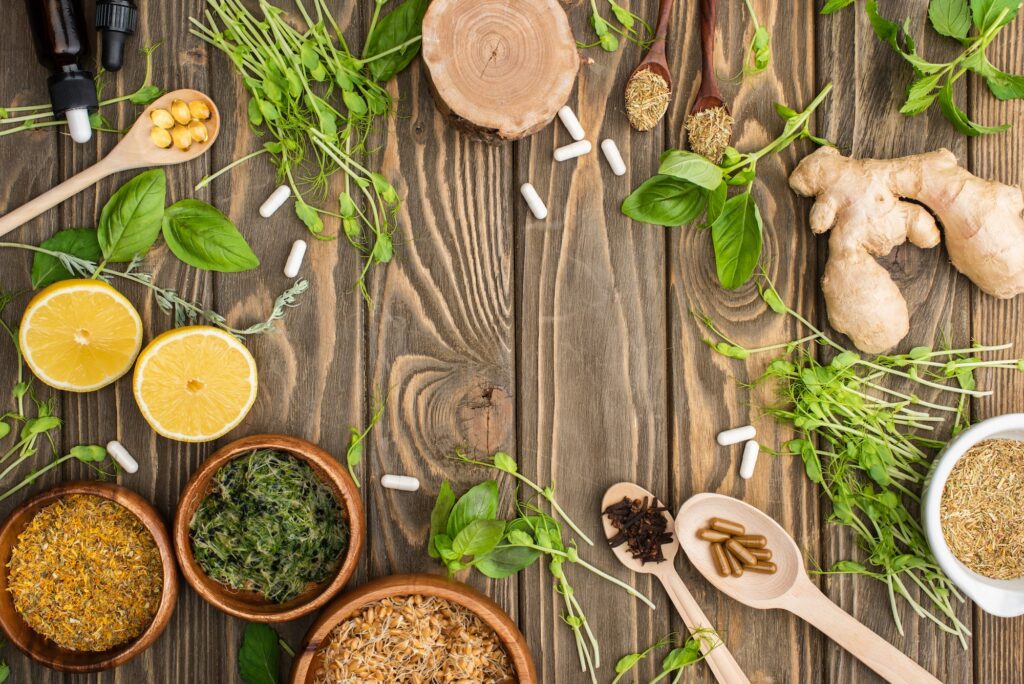 top view of pills and green herbs on wooden surface naturopathy concept